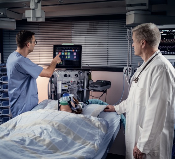 Patient in the ICU with a Doctor and nurse Looking at the PrisMax 2 Machine