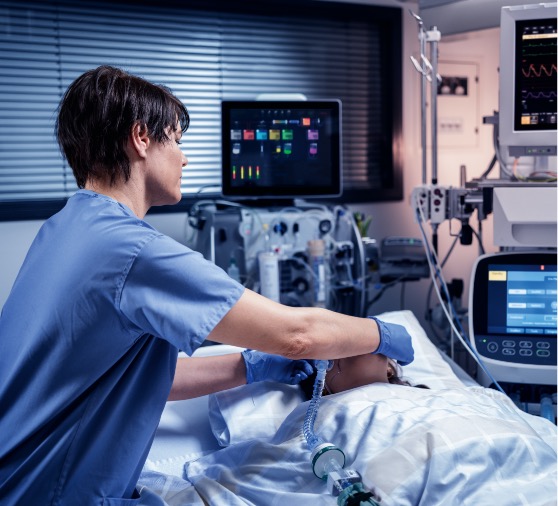 Nurse taking care of patient in the ICU with PrisMax 2 in the background