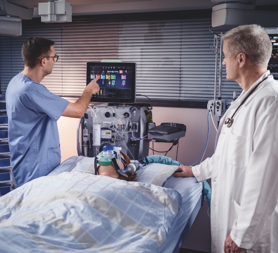 Patient in the ICU with a Doctor and nurse Looking at the PrisMax 2 Machine